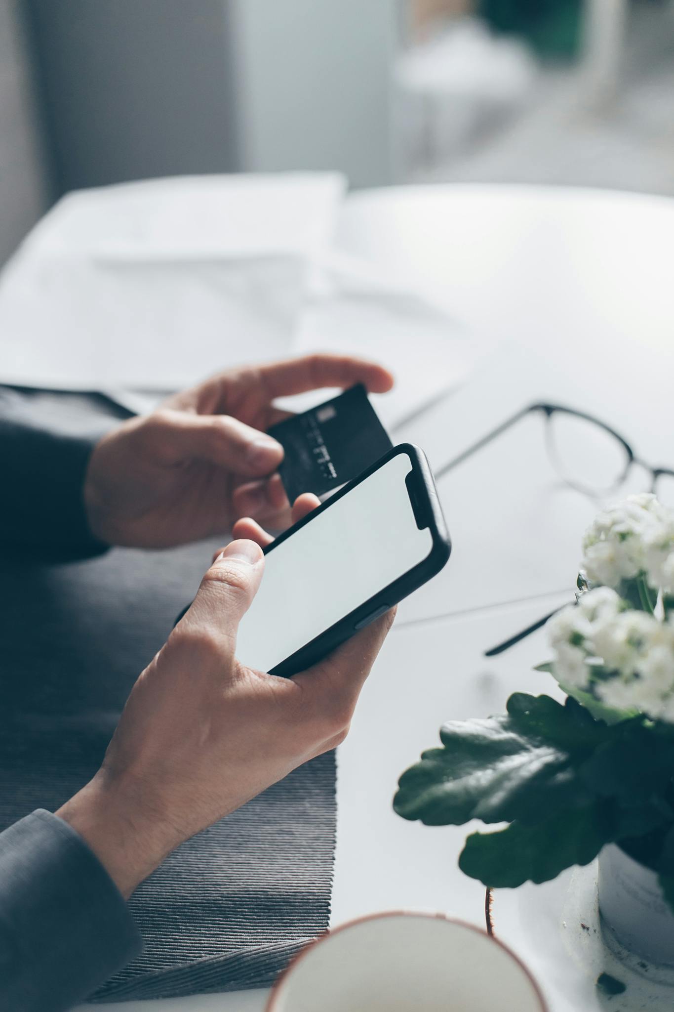 Close-up of hands holding a smartphone and a credit card, implying online payment.